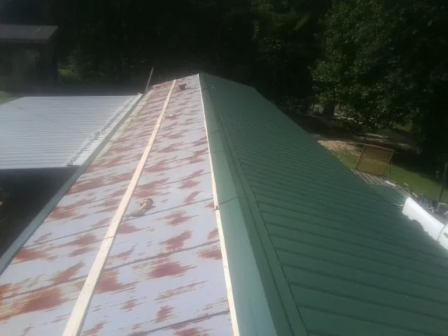 Old rusted panels beside newly installed green metal roofing — Wind Damage Roof Repair by Roofing Brothers in Taylorsville
