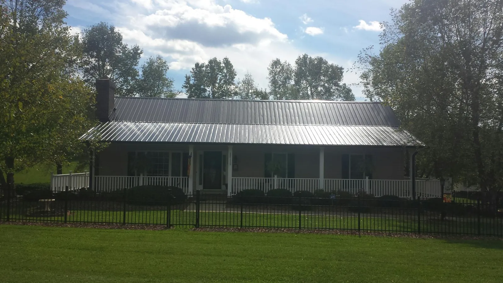 Gray metal roof on a brick ranch with a full width front porch — Gutter Guard Installation work by our crew in Taylorsville